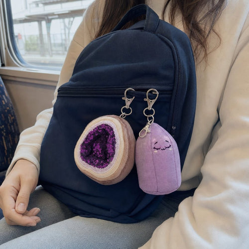 Violet and Baby Amy bag charms on a navy backpack