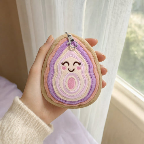 A hand holding Archie, the agate slice bag charm, by a bright window