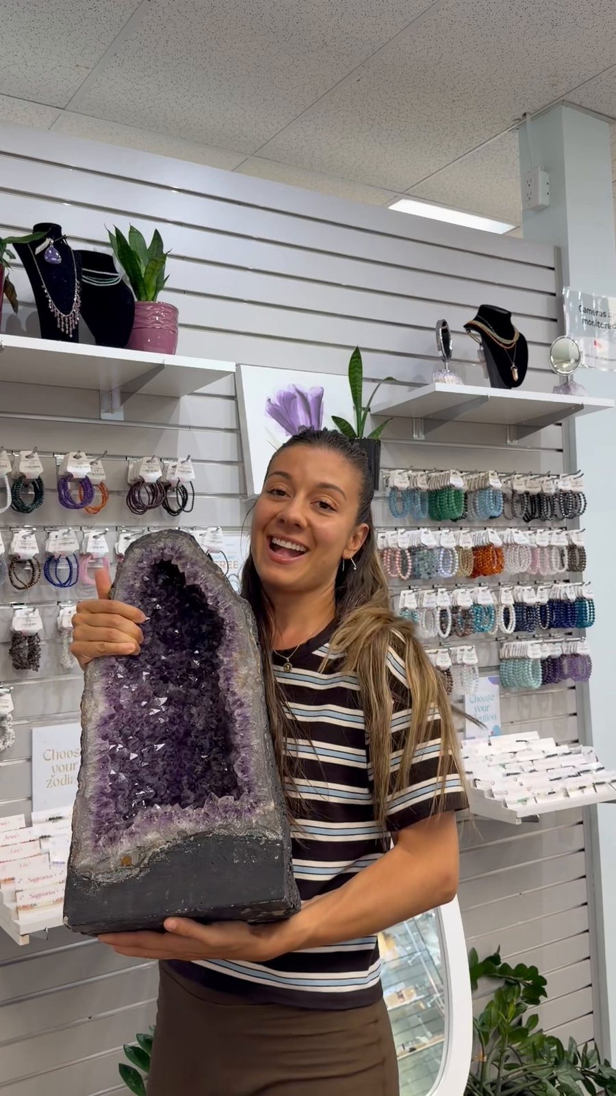 Malu Rocha, founder of Crystal Plushie, holding a giant amethyst geode in a crystal shop
