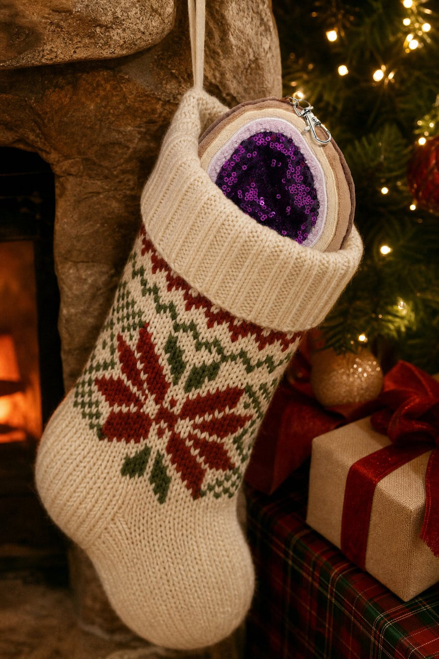 Violet the amethyst geode bag charm peeking out of a knit Christmas stocking by the fireplace
