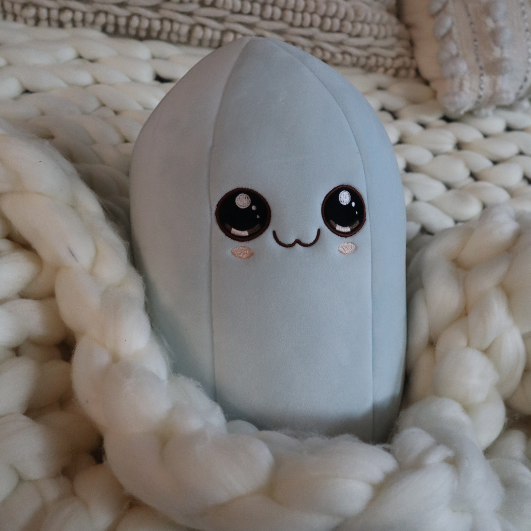 Callie the Clear Quartz Crystal Plushie resting on a chunky knit blanket
